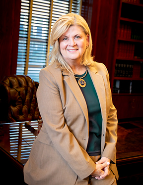 Dr. Kayla Hale in standing in her office, leaning against her desk. 