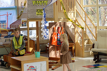 a young boy and girl walk around a pretend construction site