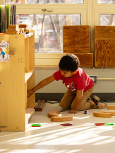 child pulls out supplies from a cabinet and places them on the floor