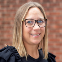 Jennifer Shepard wearing a black blouse and framed glasses.