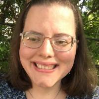 Michelle Skinner smiling, wearing glasses and a blue floral-patterned shirt.