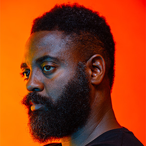 Portrait of Reginald Dwayne Betts, lit in blue, with an orange background