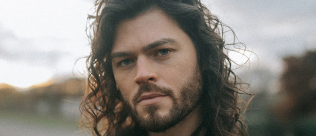 Man with long hair and short beard looks directly at you