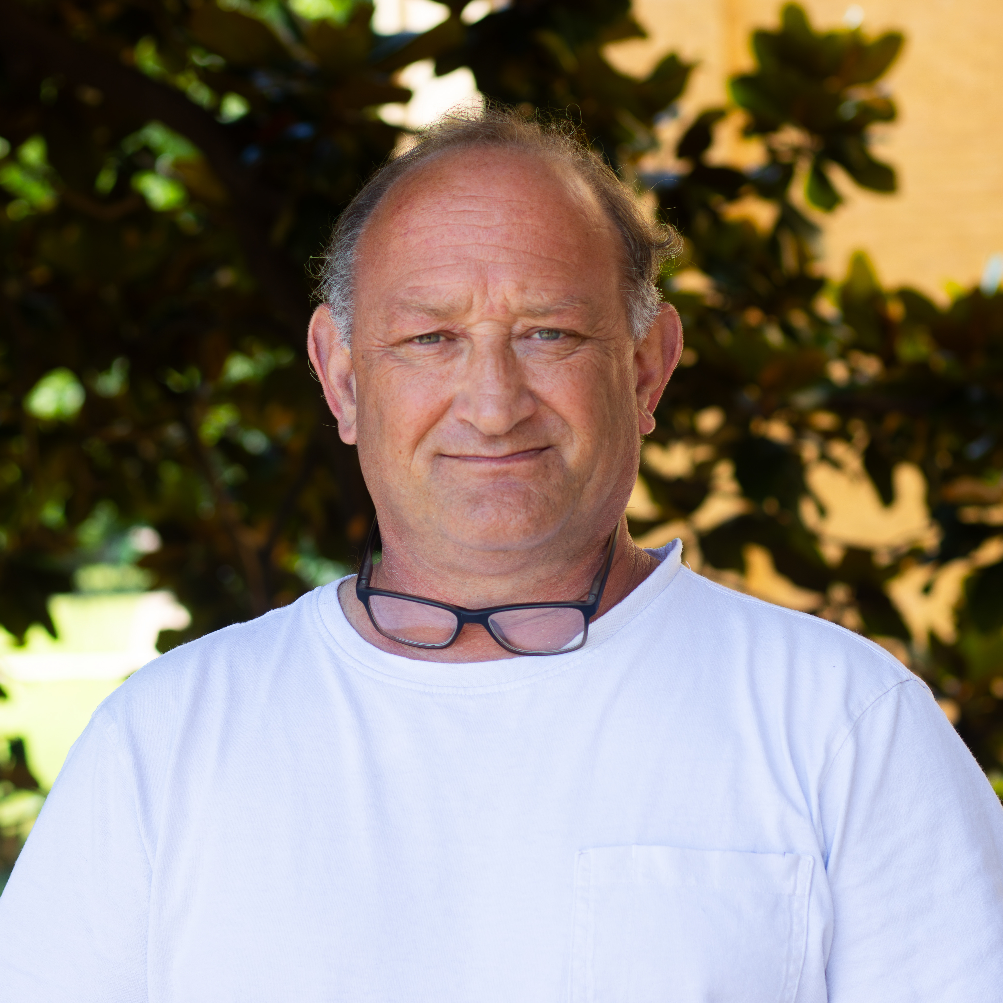 Man with glasses hanging around neck and white t-shirt