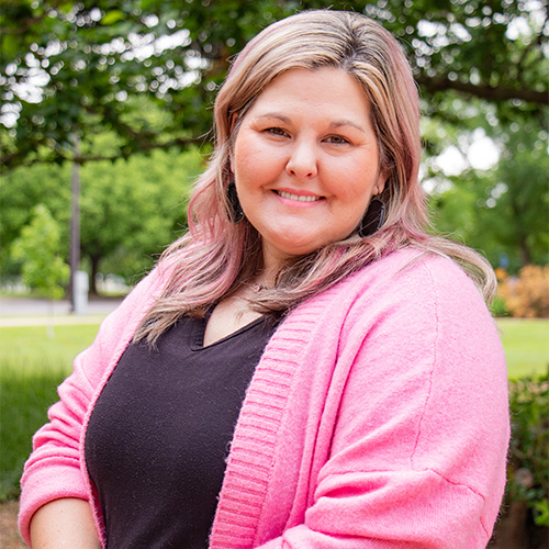 Smiling woman in a black shirt and pink cardigan