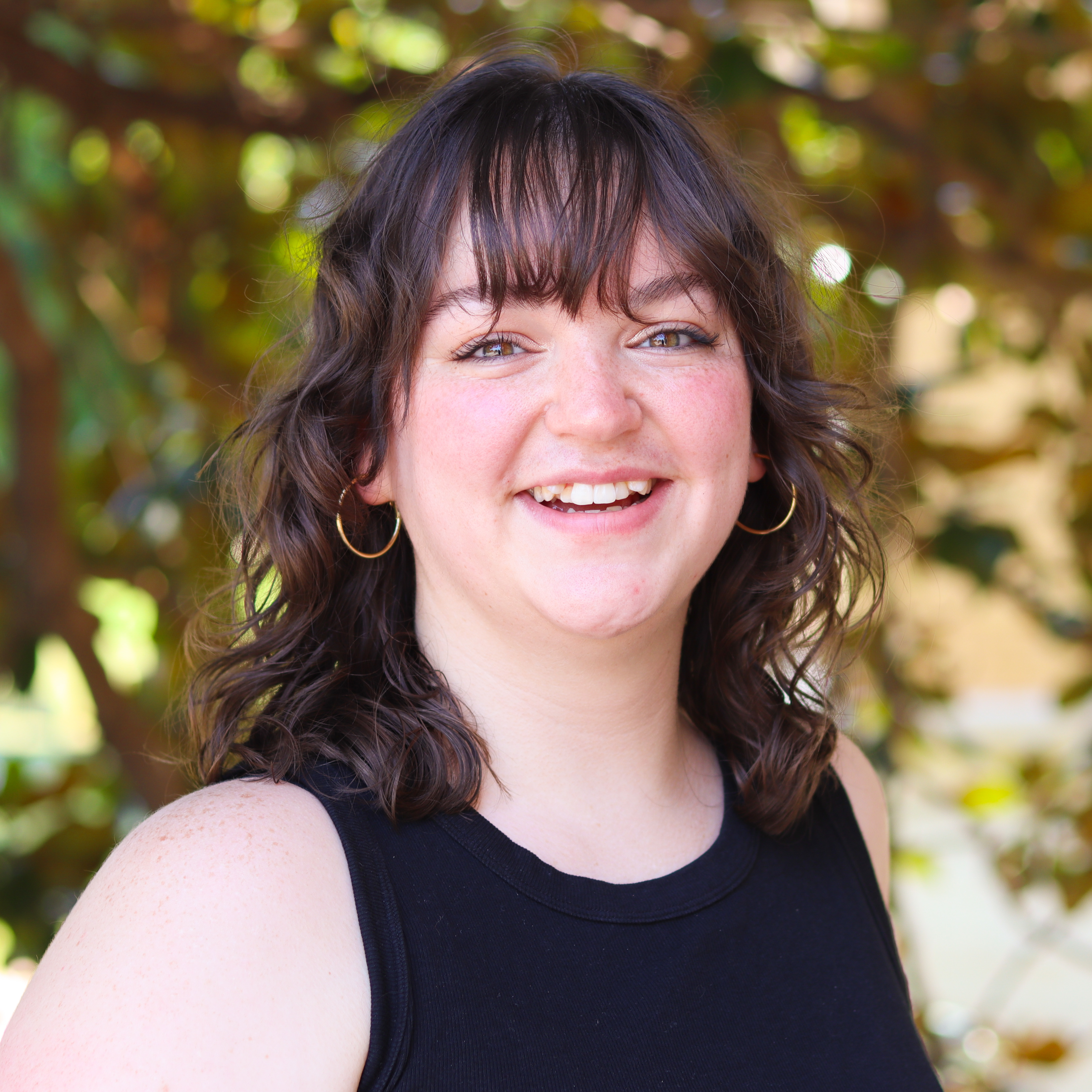 Smiling woman in a black shirt and gold hoop earrings