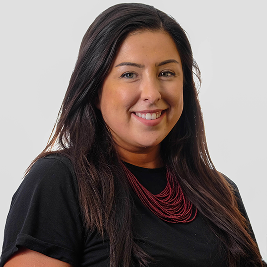 Woman smiling, wearing a black shirt and red beaded necklace