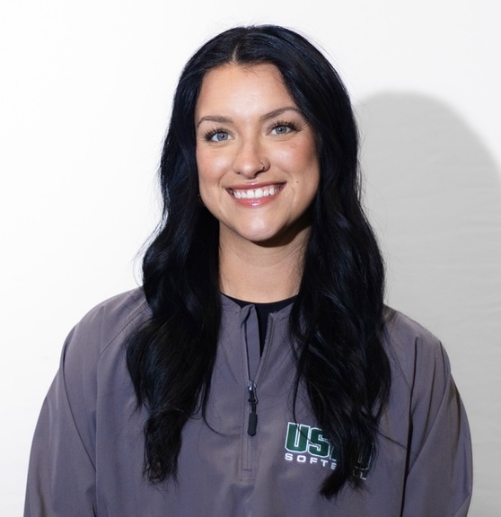 Woman with black hair smiling in a gray pullover