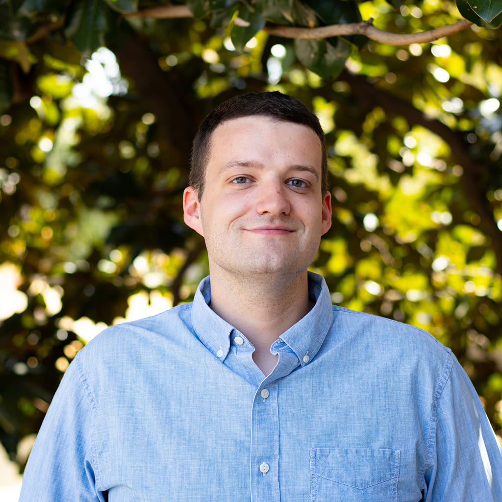 A man in blue button-up shirt smiling