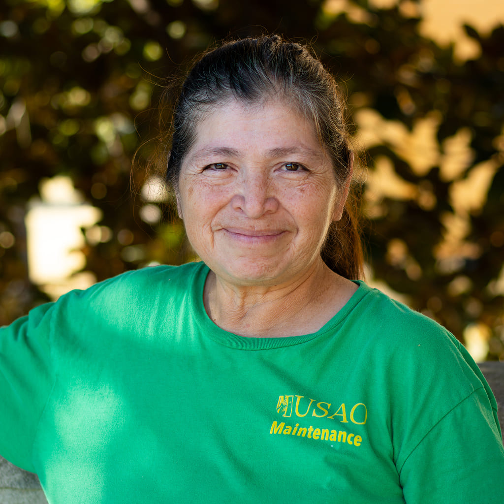 A woman in a green shirt standing and smiling