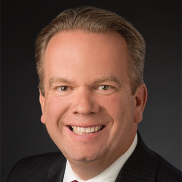 Close up of a smiling man in a black suit and white shirt