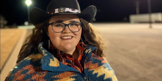 Student wearing western-style attire smiling to the camera.