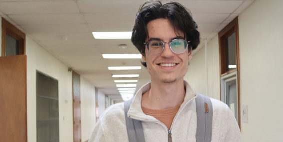 Student wearing a backpack and smiling to the camera.