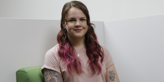 Student sitting in a green chair smiling to the camera.